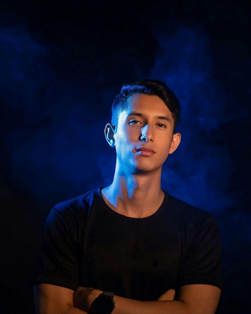 A dramatic portrait of a young man with blue backlighting, conveying a contemplative mood.